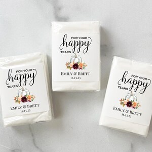 May include: Three white tissue packs with labels that read "For Your Happy Tears" in elegant script. Each label features a pumpkin illustration with floral accents and the names "Emily & Brett" with the date "11.23.23".