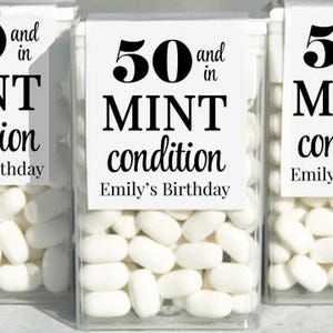 May include: Clear plastic boxes filled with white mint candies. Each box has a label that reads "50 and in MINT condition, Emily's Birthday" in black text. The boxes are arranged in a row.