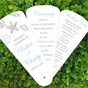 May include: A white wedding program fan with a seashell design. The front side says "Welcome to the Wedding of Robert and Christy August 8, 2025". The back side lists the wedding ceremony and reception order.