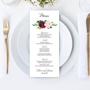 May include: A wedding menu with a floral design in shades of burgundy and pink. The menu lists appetizers, salad, entrees, and dessert. The text at the bottom reads "Olivia and James 01.15.20".
