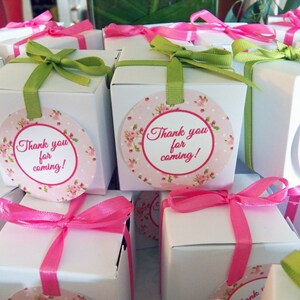 May include: White favor boxes with pink and green ribbon, decorated with a round sticker that says "Thank you for coming!"