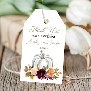 May include: White gift tag with the text "Thank You For Showering Ashley and Steven 11.20.22". The tag features a watercolor illustration of a white pumpkin and floral arrangement in shades of orange, burgundy, and peach.