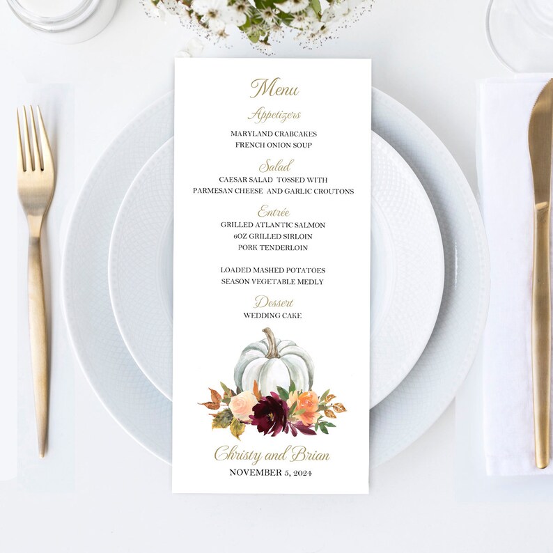 May include: A wedding menu card with a white pumpkin and floral design. The menu lists appetizers, salad, entrees, and dessert. The names "Christy and Brian" and the date "November 5, 2024" are printed at the bottom.