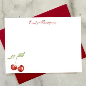 May include: White stationery with a red envelope. The stationery features a watercolor illustration of two red cherries with green leaves. The name "Emily Thompson" is printed in red script at the top.