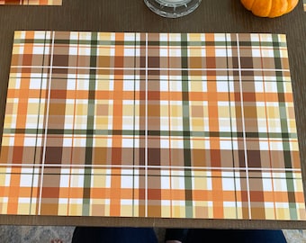 Puede incluir: Un mantel individual rectangular con un patrón de cuadros en tonos naranja, marrón, verde y blanco. El diseño presenta una cuadrícula de líneas que se cruzan, creando una estética otoñal clásica. Ideal para la decoración del comedor y la cocina.