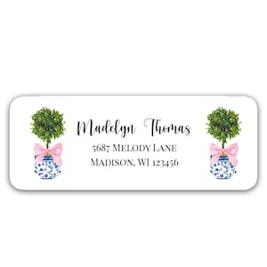 May include: A white return address label with a blue and white patterned planter with a pink bow and a green topiary. The label also includes the text "Madelyn Thomas", "5687 Melody Lane", and "MADISON, WI 123456".