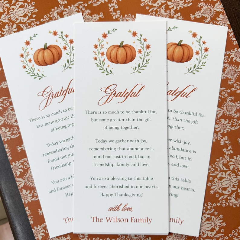 K&ouml;nnte beinhalten: Drei wei&szlig;e Thanksgiving-Karten mit einer K&uuml;rbis-Illustration und dem Wort "Grateful" in Schreibschrift. Die Karten enthalten Texte &uuml;ber Dankbarkeit und Familie, mit den S&auml;tzen "Happy Thanksgiving!" und "The Wilson Family."