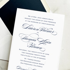May include: A white wedding invitation with navy blue text. The invitation includes the names Lauren Palmer and Thomas Kevin Brown, along with the date, time, and location of the ceremony. The invitation is placed inside a white envelope with a navy blue interior.