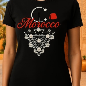 May include: Black t-shirt with a red and white graphic design. The design includes the word "Morocco" in red script, a white crescent moon, and a geometric triangle with floral accents. A red fez is also included.