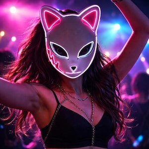 May include: A white cat-shaped mask with pink and white neon lights. The mask has large eye openings and a small nose and mouth. The person is wearing a black top and gold chain necklaces. The background is a blurry scene with pink and blue lights.