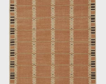 May include: A rectangular rug with a terracotta-colored background and a geometric pattern. The design features vertical cream-colored lines with diamond-shaped accents, framed by a border of dark brown and cream rectangles. The rug has a fringed edge.
