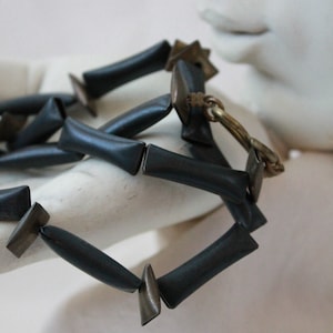 May include: A black and silver necklace with rectangular and triangular beads.