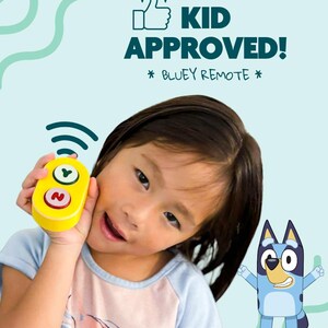 May include: A young child holds a yellow toy remote control with green and red buttons. The text "KID APPROVED! * BLUEY REMOTE *" is displayed above the child. A cartoon image of Bluey the dog is on the right.