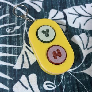Bluey Toy - Front view. Green/Red buttons with a yellow body and a keychain.