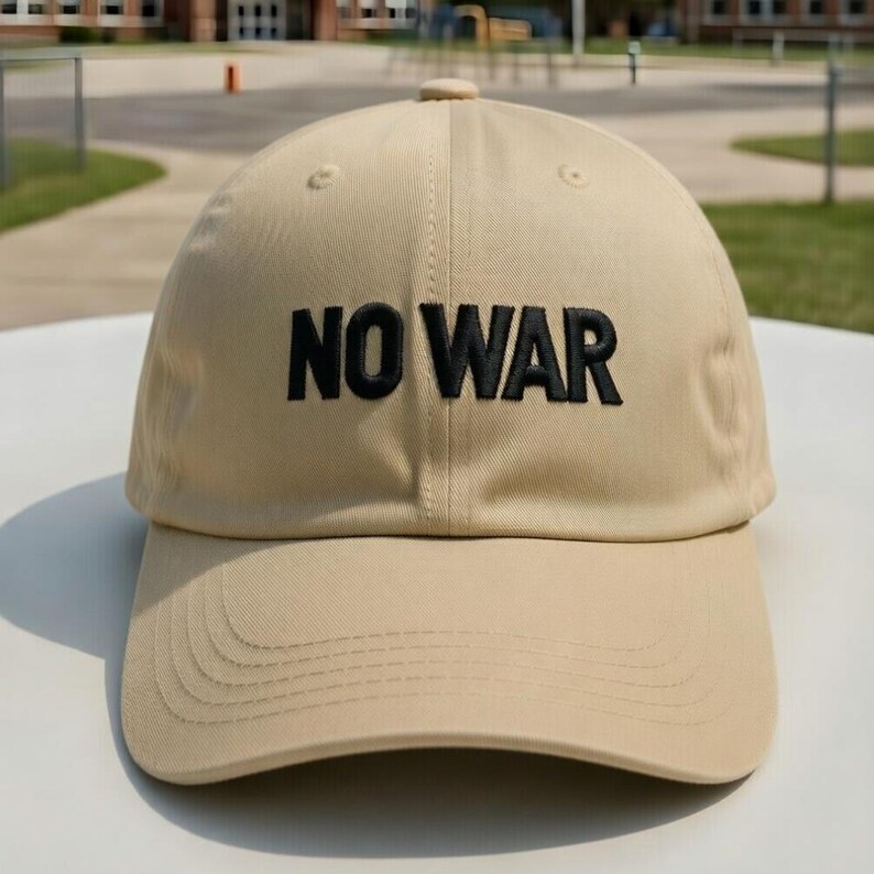 May include: A tan baseball cap with the embroidered text "NO WAR" in black. The cap has a curved brim and a button on top. The hat is made of a durable fabric and is suitable for everyday wear.