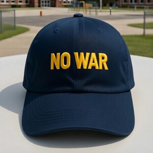 May include: A navy blue baseball cap with the embroidered text "NO WAR" in yellow. The cap has a curved brim and a button on top. The hat is sitting on a white surface.