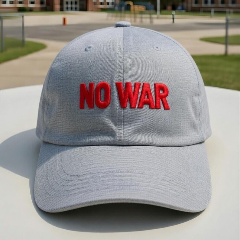 May include: A light gray baseball cap with the embroidered text "NO WAR" in red. The cap has a curved brim and a fabric texture. The hat is sitting on a white surface.
