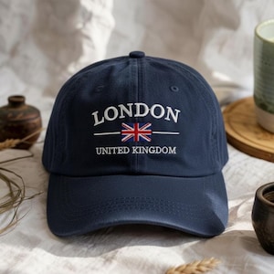 May include: Navy blue baseball cap with the word "LONDON" embroidered in white, along with the Union Jack flag and the words "UNITED KINGDOM". The cap is a classic style, suitable for casual wear.