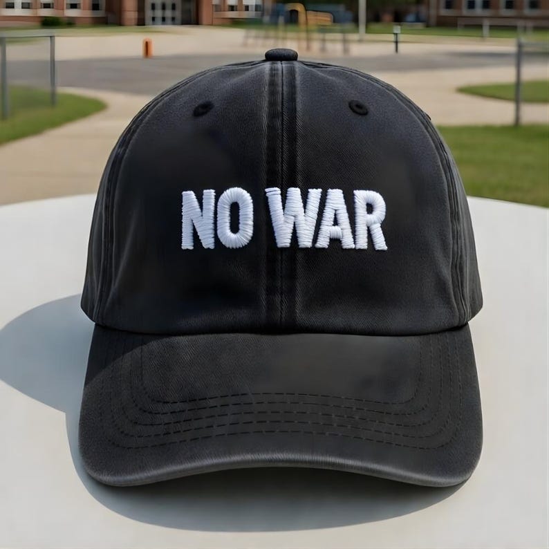 May include: A black baseball cap with the white embroidered text "NO WAR" across the front. The cap has a curved brim and a rounded top. The background shows a school building and a grassy area.