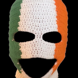May include: Crocheted balaclava in the colors of the Irish flag: green, white, and orange. The balaclava has eye and mouth openings. The knitted hat is a winter accessory.