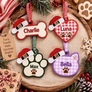 May include: Four personalized Christmas ornaments featuring embroidered names Charlie, Luna, Max, and Bella. The ornaments are shaped like a bone, heart, paw print, and cat head, each topped with a miniature red Santa hat and a checkered hanging ribbon.