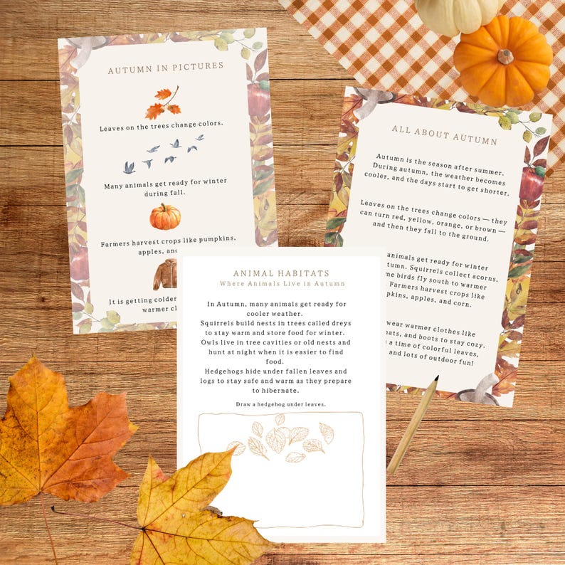 May include: Three educational autumn-themed cards with text and illustrations, including pumpkins, leaves, and animals. The cards are on a wooden surface with fall leaves and pumpkins.