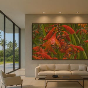 May include: A large framed artwork featuring vibrant orange flowers with water droplets against a green background. The artwork hangs above a beige sofa in a modern living room with large windows overlooking a tropical landscape.