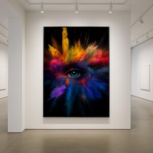 May include: A large framed art print featuring a vibrant eye with a blue iris at the center. The eye is surrounded by a burst of colorful powder in shades of yellow, orange, red, purple, and blue against a black background. The artwork is displayed in a modern art gallery.