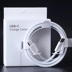 Könnte beinhalten: Ein weißes USB-C-Ladekabel mit weißer Verpackung. Auf der weißen Box steht "USB-C Charge Cable". Das Kabel ist aufgerollt und wird von weißen Kartonhaltern gehalten.