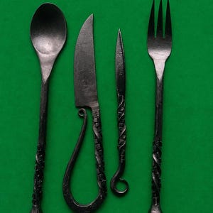 May include: A set of four dark gray forged metal utensils including a spoon, a knife with a looped handle, a thin pointed tool, and a three-tined fork. Each piece features a textured, twisted handle design ending in a rounded metal knob.