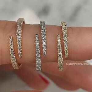 Könnte beinhalten: Sechs kleine Creolen, jeweils besetzt mit kleinen, funkelnden Steinen. Die Ohrringe sind in Gold- und Silbertönen gehalten. Das Bild zeigt die Ohrringe auf einem Finger mit rotem Nagellack.