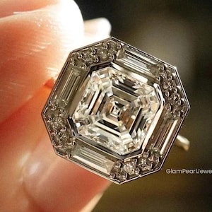 May include: An eye-catching, octagonal ring featuring a large, square-cut diamond at its centre. The central stone is encircled by a halo of smaller, rectangular-cut diamonds and a border of tiny round diamonds. The ring is set in a gold band.
