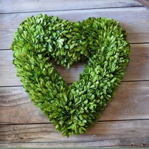 May include: A green boxwood heart-shaped wreath. The wreath is made of natural boxwood and is perfect for adding a touch of greenery to your home decor.