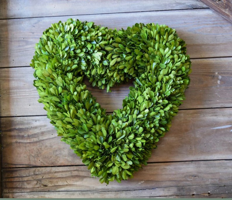 May include: A green boxwood heart-shaped wreath. The wreath is made of natural boxwood and is perfect for adding a touch of greenery to your home decor.