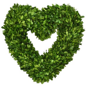 May include: A green heart-shaped boxwood wreath. The wreath is made of artificial boxwood leaves and is perfect for adding a touch of greenery to your home decor.