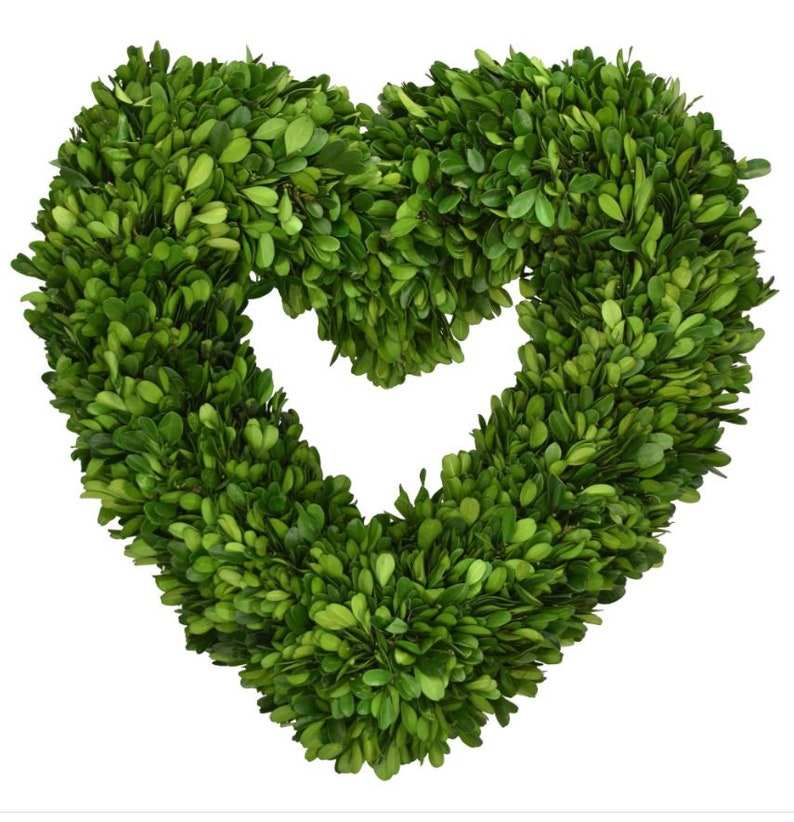 May include: A green heart-shaped boxwood wreath. The wreath is made of artificial boxwood leaves and is perfect for adding a touch of greenery to your home decor.