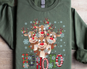 May include: Military green sweatshirt featuring a festive design. The design includes a group of reindeer with red noses, wearing scarves, and surrounded by snowflakes. The word "HOHOHO" is printed below the reindeer.