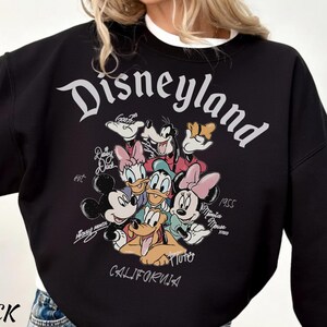May include: Black Disneyland sweatshirt featuring a graphic of Mickey Mouse, Minnie Mouse, Donald Duck, Daisy Duck, Goofy, and Pluto. The word "Disneyland" is arched across the top, with "California" at the bottom. The sweatshirt also has the word "Black" on the bottom left.