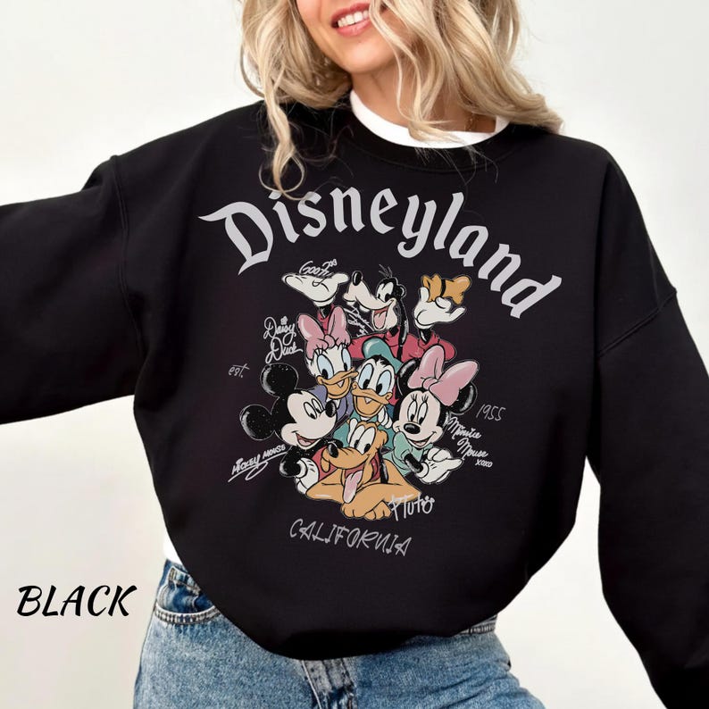 May include: Black Disneyland sweatshirt featuring a graphic of Mickey Mouse, Minnie Mouse, Donald Duck, Daisy Duck, Goofy, and Pluto. The word "Disneyland" is arched across the top, with "California" at the bottom. The sweatshirt also has the word "Black" on the bottom left.