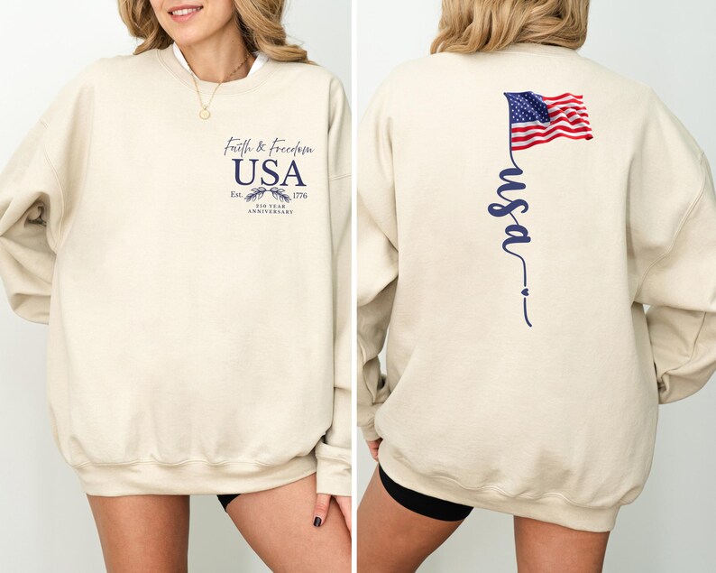 Puede incluir: Sudadera beige con el texto "Faith & Freedom USA" y un gr&aacute;fico de &aacute;guila en la parte delantera. La parte trasera presenta una bandera estadounidense ondeando y la palabra "usa" en cursiva. La sudadera celebra el 200 aniversario.