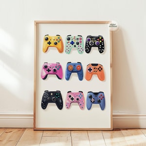 May include: A framed print featuring nine colorful video game controllers. The controllers are in various colors, including yellow, pink, blue, and black, with different button and joystick designs. The print has a "digital download" sticker.