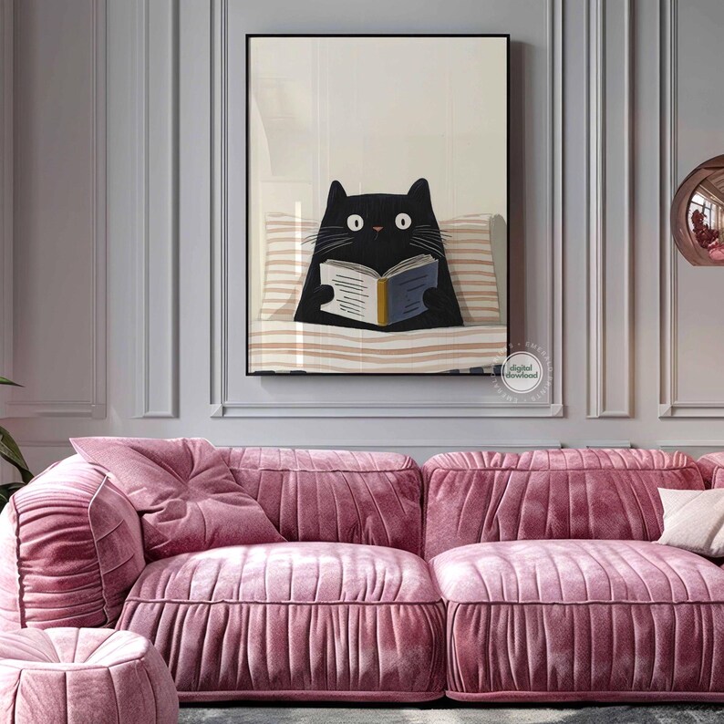May include: A framed art print featuring a black cat reading a book while lying on a striped pillow. The artwork is set against a neutral background and is displayed above a pink velvet sofa.