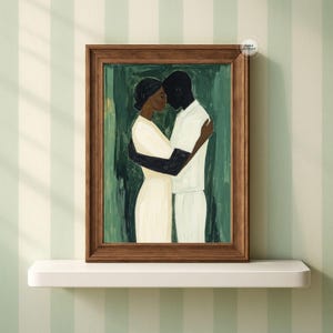 May include: A framed art print featuring an embrace between two figures. The artwork depicts a couple in a tender embrace, with one figure in white and the other in black. The background is a textured green, and the frame is brown.