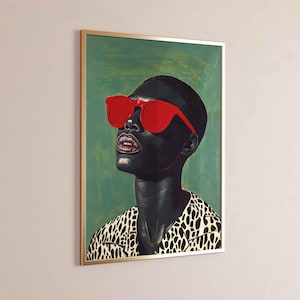 May include: Framed art print featuring a portrait of a person with dark skin wearing bright red sunglasses. The person is looking upwards, with a green background and a gold frame. The person is wearing a black and white patterned shirt.
