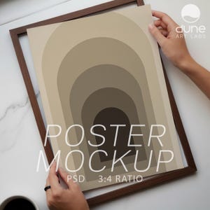 May include: A framed poster mockup featuring a minimalist design of concentric arches in shades of beige and brown. The poster is held in a dark brown wooden frame. The text "POSTER MOCKUP" is displayed prominently on the poster, along with "PSD 3:4 RATIO".