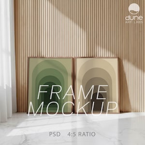 Könnte beinhalten: Zwei gerahmte Kunstdrucke mit einem geschichteten Bogendesign in Grün- und Beigetönen. Die Rahmen lehnen an einer Wand mit Holzpaneelen. Der Text "FRAME MOCKUP" ist auf den Drucken zu sehen. Der untere Teil des Bildes zeigt "PSD 4:5 RATIO".