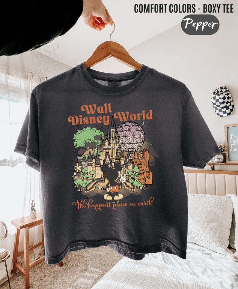 May include: Dark gray boxy tee with a Walt Disney World graphic. The design features a castle, Spaceship Earth, and Mickey Mouse. Text includes "Walt Disney World" and "The happiest place on earth". The shirt is labeled "Comfort Colors - Boxy Tee" and the color is "Pepper".