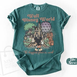 May include: Teal-colored t-shirt featuring a graphic of Walt Disney World with Mickey Mouse. The design includes the text "Walt Disney World" and "The happiest place in earth". The shirt has a crew neck and short sleeves.