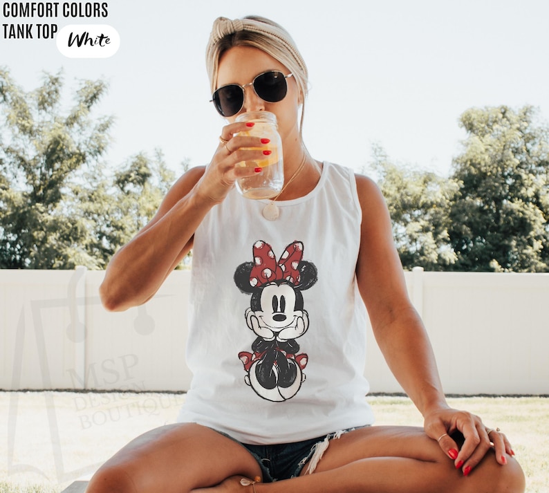 May include: A white tank top featuring a graphic print of a cartoon mouse with a red and white polka dot bow. The text COMFORT COLORS TANK TOP White is visible in the upper left corner, and the text MSP DESIGN BOUTIQUE is visible on the lower left.