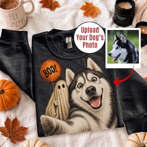 May include: A black crewneck sweatshirt featuring a graphic of a smiling Siberian Husky taking a selfie with a ghost holding an orange balloon with the text BOO! printed on it. The design includes a placeholder for a custom dog photo.